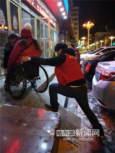 志愿者推拽殘友的輪椅上臺階。
