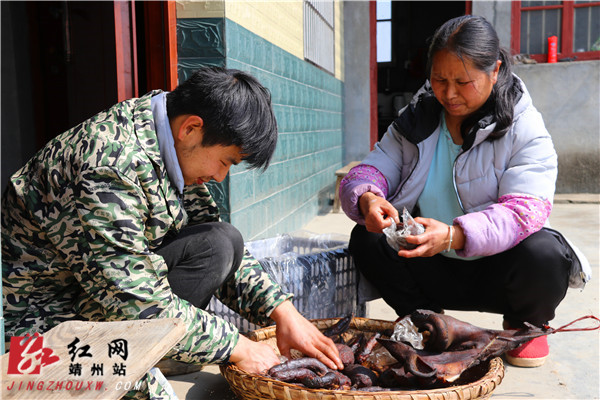 黃水林正蹲著和媽媽一起仔細地將臘腸和血丸子打包裝袋。易子明 攝